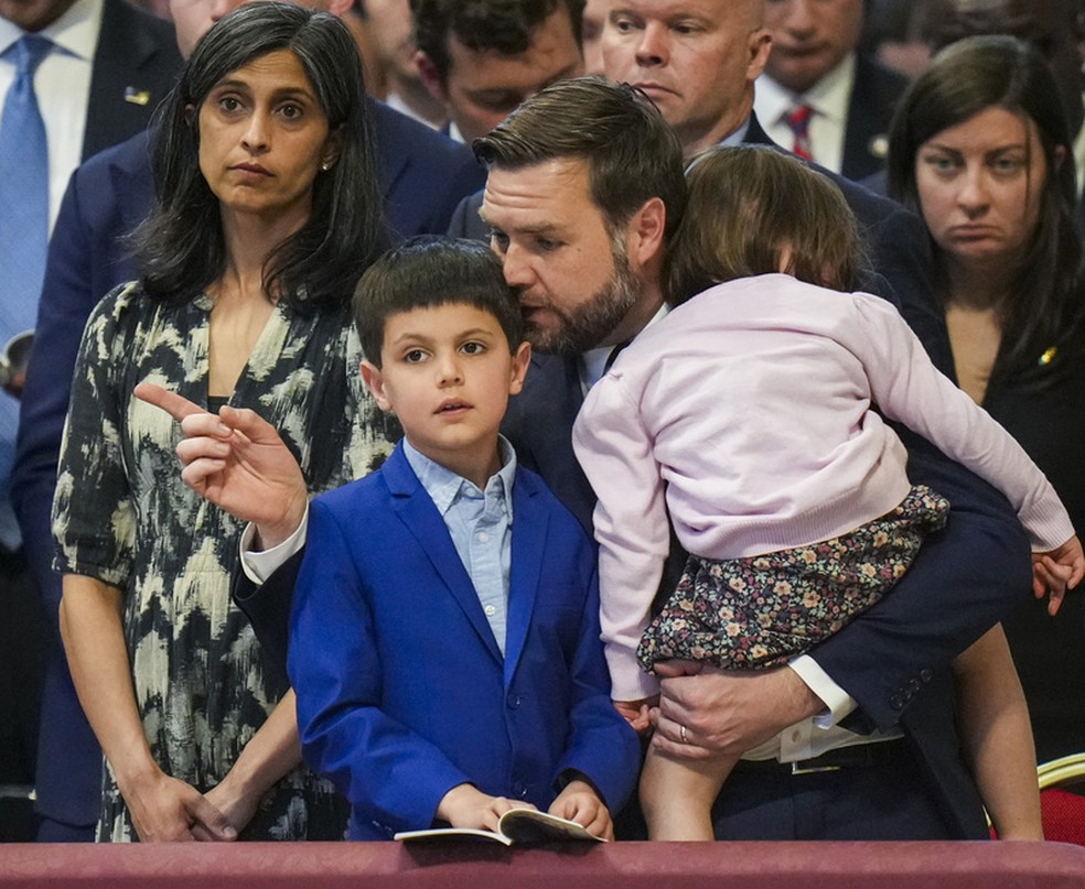 A família Vance: Usha, esposa do vice-presidente J.D. Vance, e as crianças Vivek e Mirabel, de costas para a câmera e no colo do pai — Foto: Alessandra Tarantino/AP