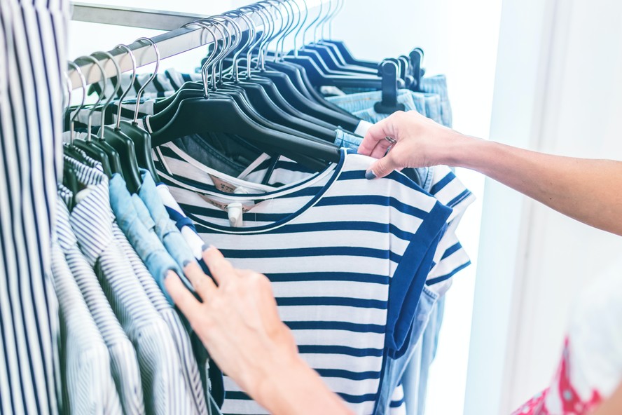 Mulher observa uma peça de roupa; compras; comércio; compra; shopping; loja