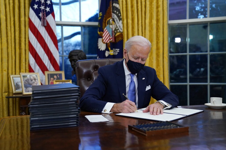 President Joe Biden signs his first executive orders in the Oval Office of the White House on Wednesday, Jan. 20, 2021, in Washington. (AP Photo/Evan Vucci)