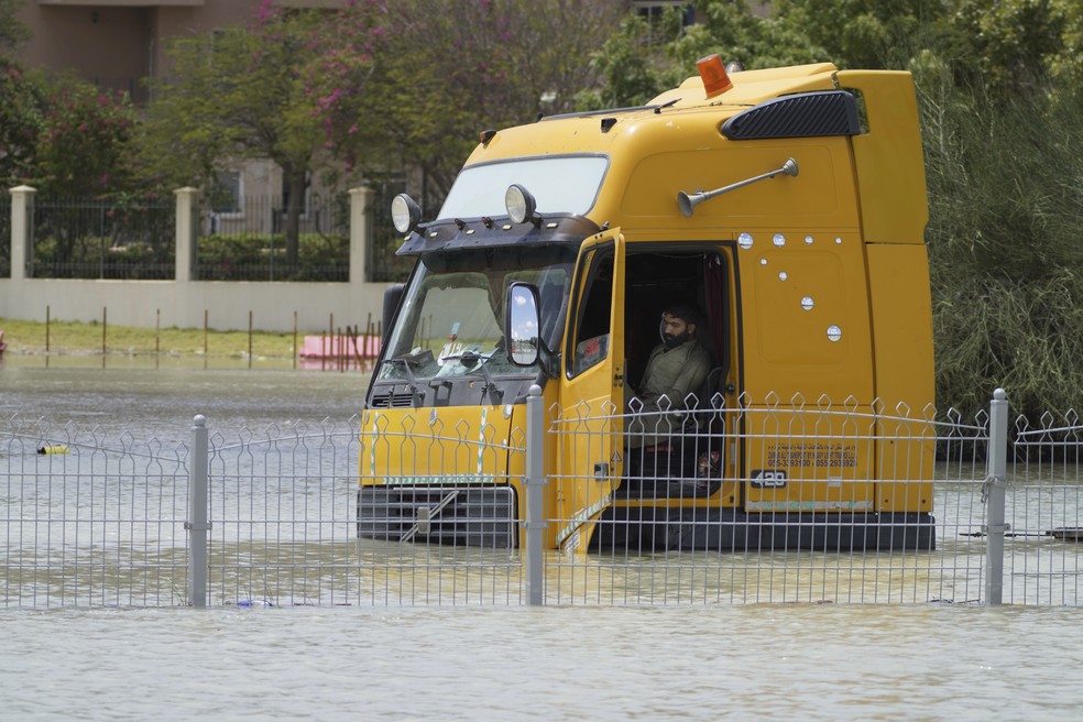 Homem sentado em um caminhão preso nas enchentes em Dubai — Foto: Jon Gambrell/AP