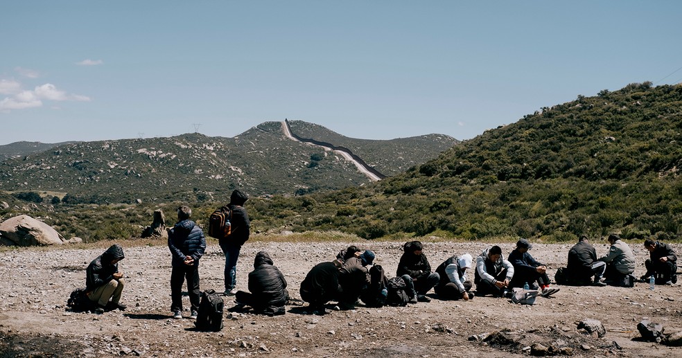 Imigrantes ilegais aguardam em uma estrada para serem transportados para processamento após cruzar a fronteira EUA-México em Campo, na Califórnia — Foto: Mark Abramson/Bloomberg