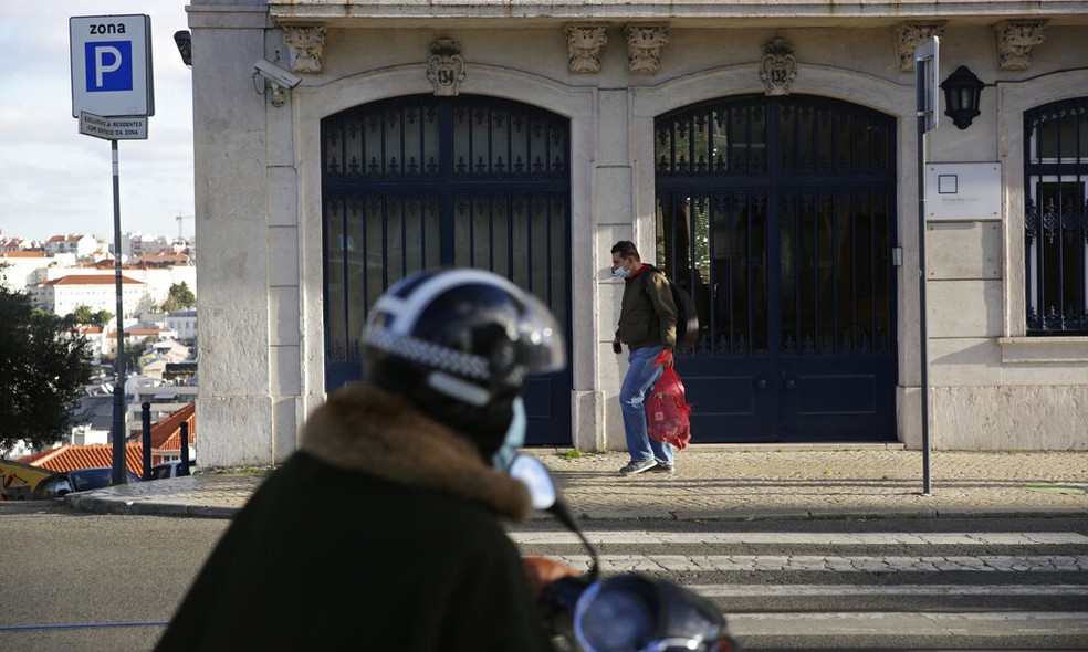 Um homem com máscara para se proteger da covid-19 caminha por uma rua de Lisboa, Portugal — Foto: Armando Franca/AP Photo