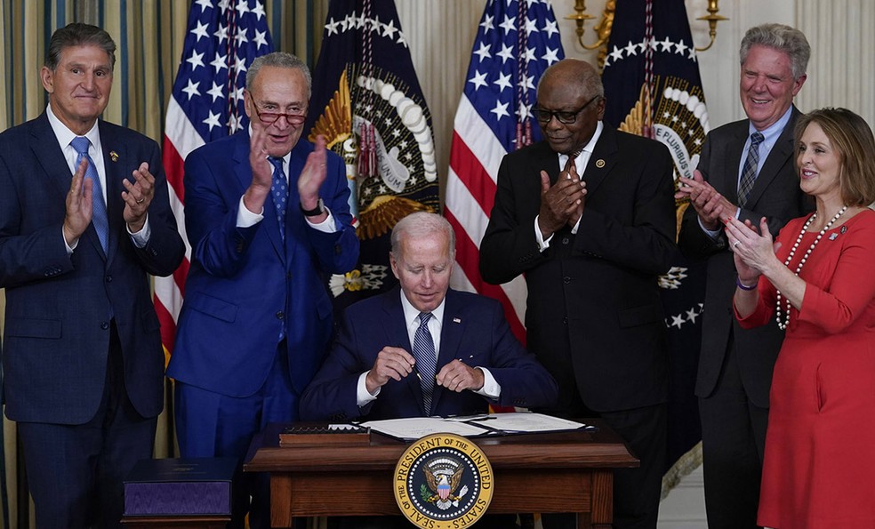 Biden (no centro), com assessores e parlamentares, durante assinatura na Casa Branca de leis para revigorar setor de indústria estratégica e verde dos EUA — Foto: Susan Walsh/AP-16/8/2022
