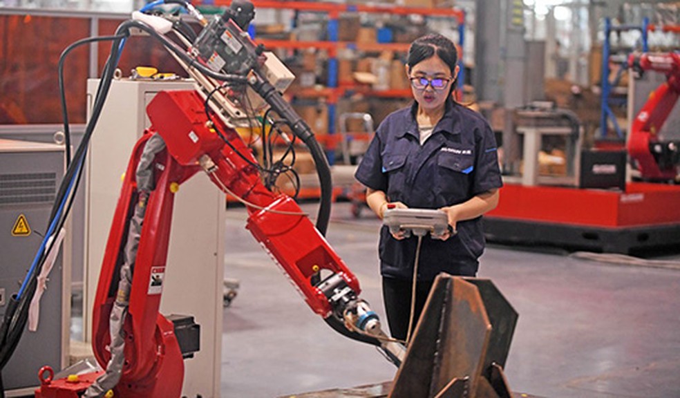 Uma engenheira ajusta o braço de um robô em uma fábrica robotizada em Shenyang, China — Foto: Agência de Notícias Yang Qing Xinhua/Newscom