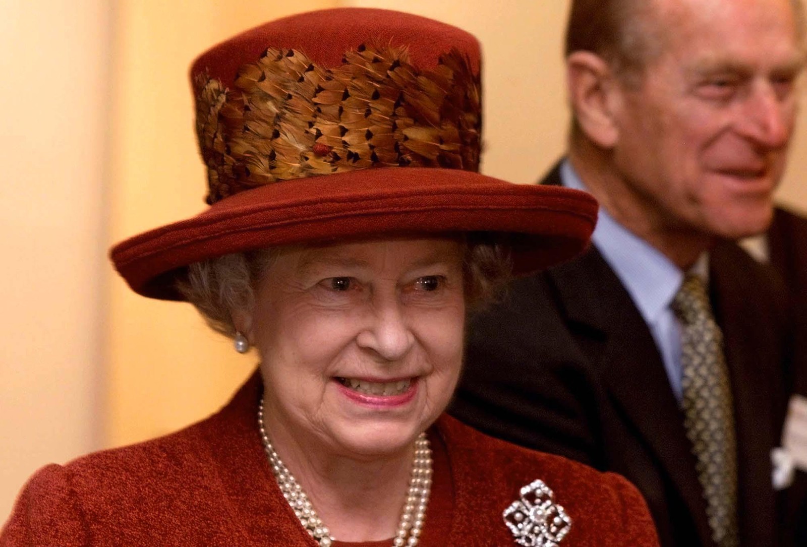 Os chapéus de Elizabeth II também eram marca registrada. Aqui, um adornado com penas de faisão, em foto com o marido ao fundo, em novembro de 2000 — Foto: FINDLAY KEMBER/AP