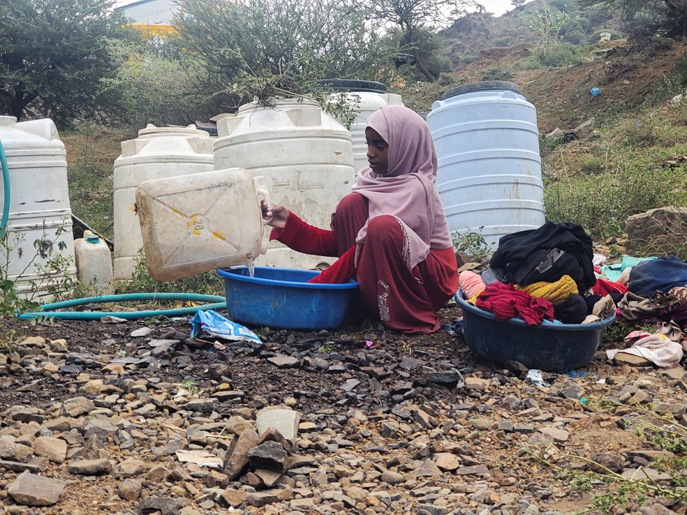 Uma mulher lava roupas em um acampamento improvisado para pessoas deslocadas pelos confrontos entre combatentes houthis alinhados ao Irã e forças do governo iemenita apoiadas pela Arábia Saudita, na província de Taiz, no Iêmen, em 14 de setembro de 2026 — Foto: REUTERS/Stringer
