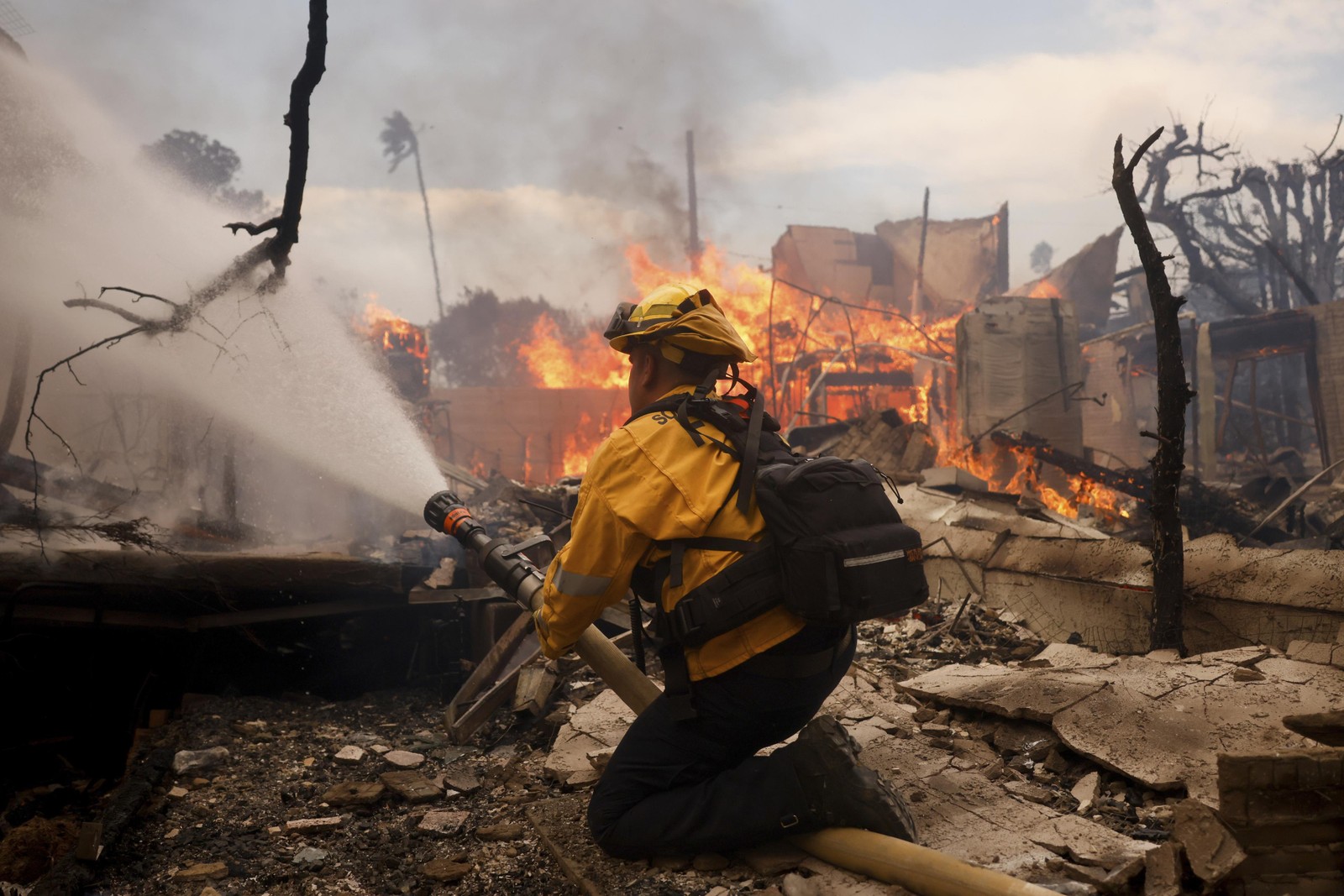 Bombeiro combate incêndio no bairro de Pacific Palisades, um dos mais atingidos pelo fogo em Los Angeles — Foto: Etienne Laurent/AP