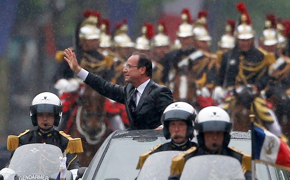 Todo ensopado, François Hollande (que dispensou o guarda-chuva) desfila pela famosa avenida Champs-Elysees, após cerimônia de posse — Foto: Regis Duvignau/AP
