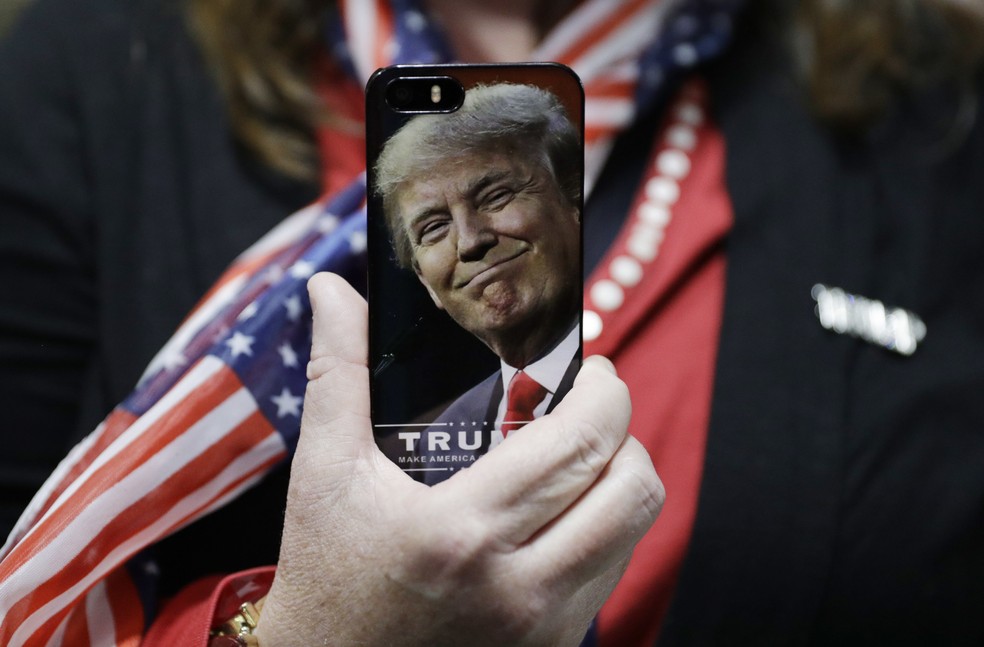 Mulher segura um celular com a imagem de Trump — Foto: AP Photo