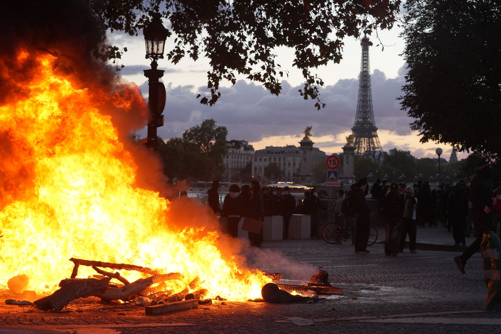Um incêndio tem início durante uma manifestação em Paris, na França, no sábado, 17 de outubro. Manifestantes atacaram prédios públicos franceses e saquearam lojas em várias cidades, incluindo Paris, durante protestos contra o alto custo de vida que reuniram mais de meio milhão de pessoas, evidenciando os desafios que o país enfrenta às vésperas das eleições presidenciais do próximo ano — Foto: Nathan Laine/Bloomberg