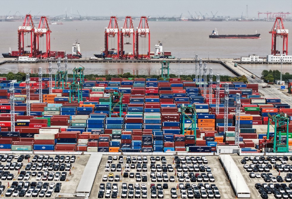Imagem aérea mostra veículos elétricos (VE) para exportação e contêineres estacionados em um porto de Xangai, China, em 13 de abril de 2025 — Foto: China Daily via REUTERS