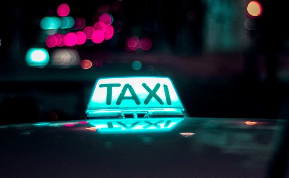 Taxistas com carros em uma rua da cidade.