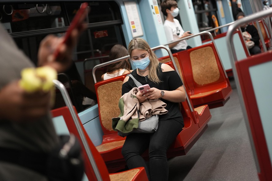 A woman wearing a face mask uses her cellphone in a subway train in Lisbon, Friday, Oct. 22, 2021. Portugal has scrapped many of its remaining COVID-19 restrictions but the wearing of face masks is st