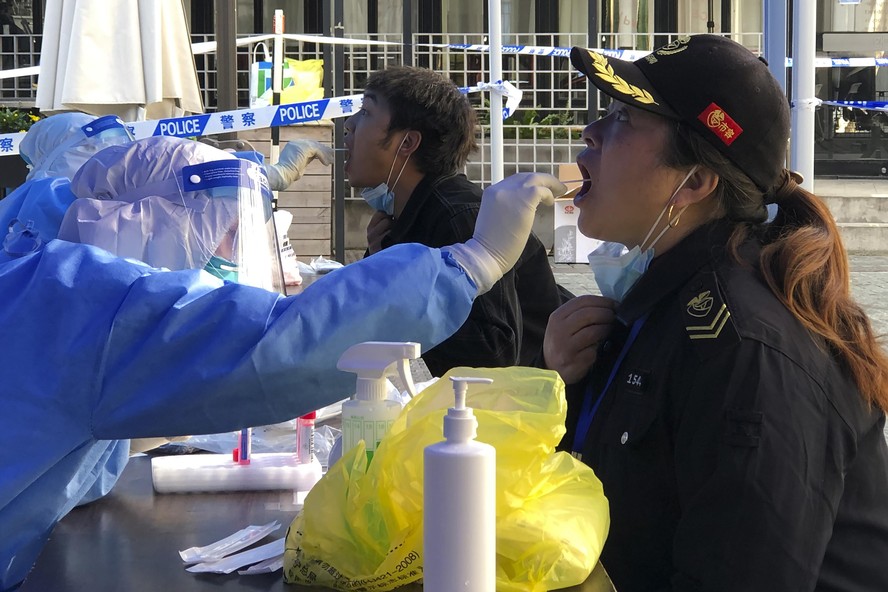 A medical worker collects sample swab sample from residents in a lockdown area in the Jingan district of western Shanghai, Monday, April 4, 2022. China has sent more than 10,000 health workers from ac