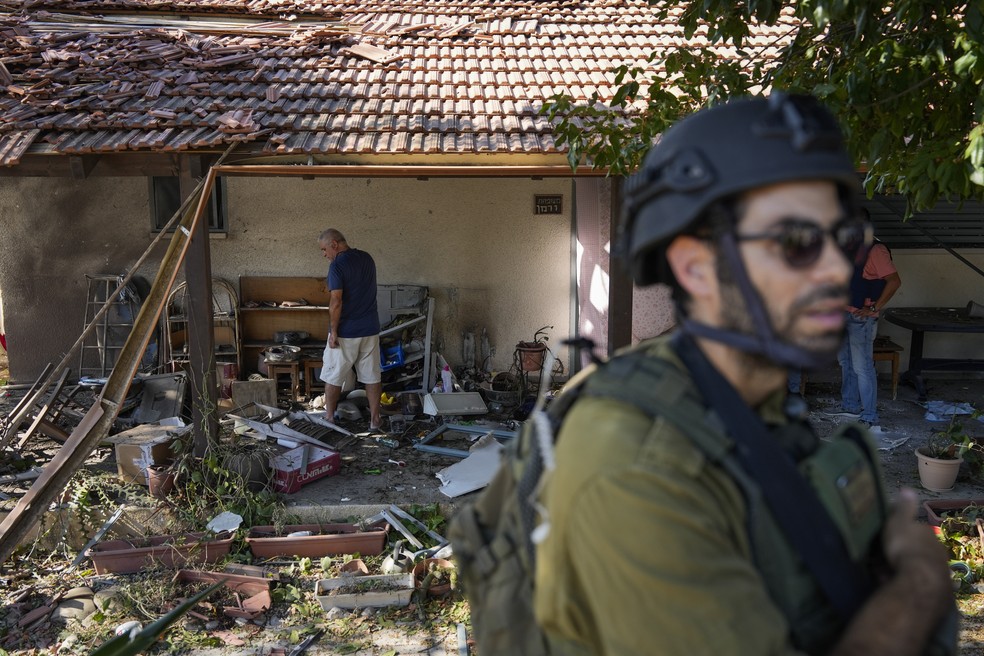 Forças de segurança de Israel e moradores avaliam danos em uma casa após ataque feito do Líbano — Foto: Baz Ratner/AP Photo