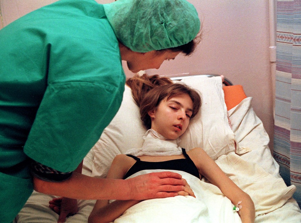 Uma profissional de saúde atende uma jovem de 17 anos que se recupera de uma cirurgia para remover um tumor cancerígeno na unidade de terapia intensiva do Instituto de Endocrinologia em Kiev, Ucrânia, em 30 de novembro de 2000, quase 15 anos após a explosão e o incêndio na usina nuclear de Chernobil — Foto: Efrem Lukatsky/AP