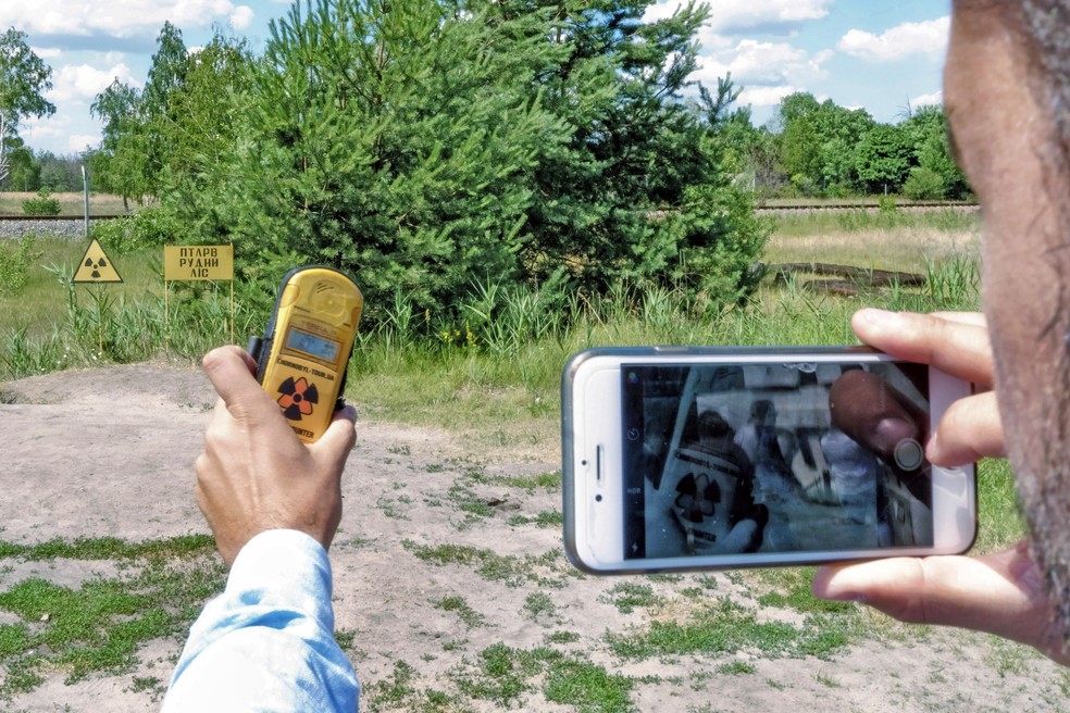 Turista fotografando nível de radiação na cidade de Pripyat, cidade mais próxima de Chernobil — Foto: Vincent Mundy/Bloomberg