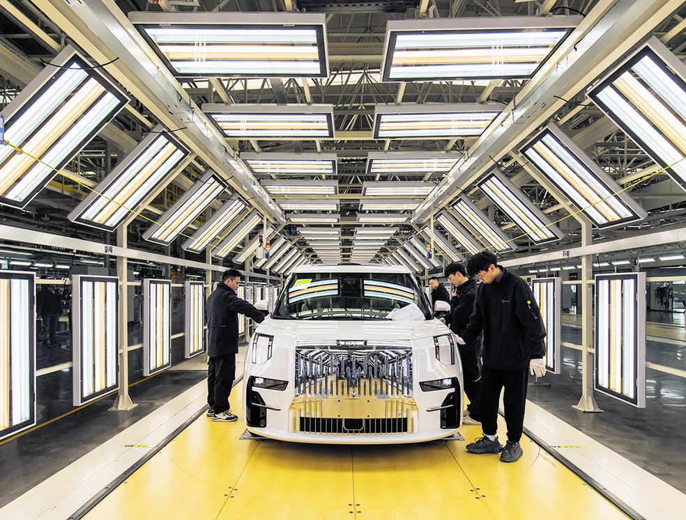 Trabalhadores na linha de produção da fábrica de veículos elétricos chinesa Geely, que utiliza materiais críticos — Foto: Qilai Shen/Bloomberg