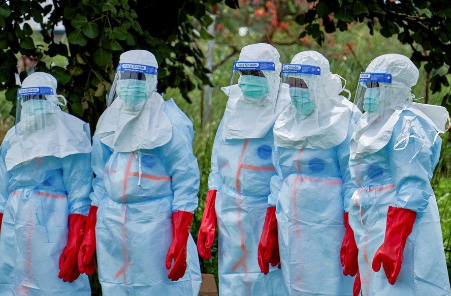 Trabalhadores da Cruz Vermelha se reúnem para desinfetar o hospital geral de Rwampara antes de lidar com o corpo de uma pessoa que morreu de Ebola na República Democrática do Congo