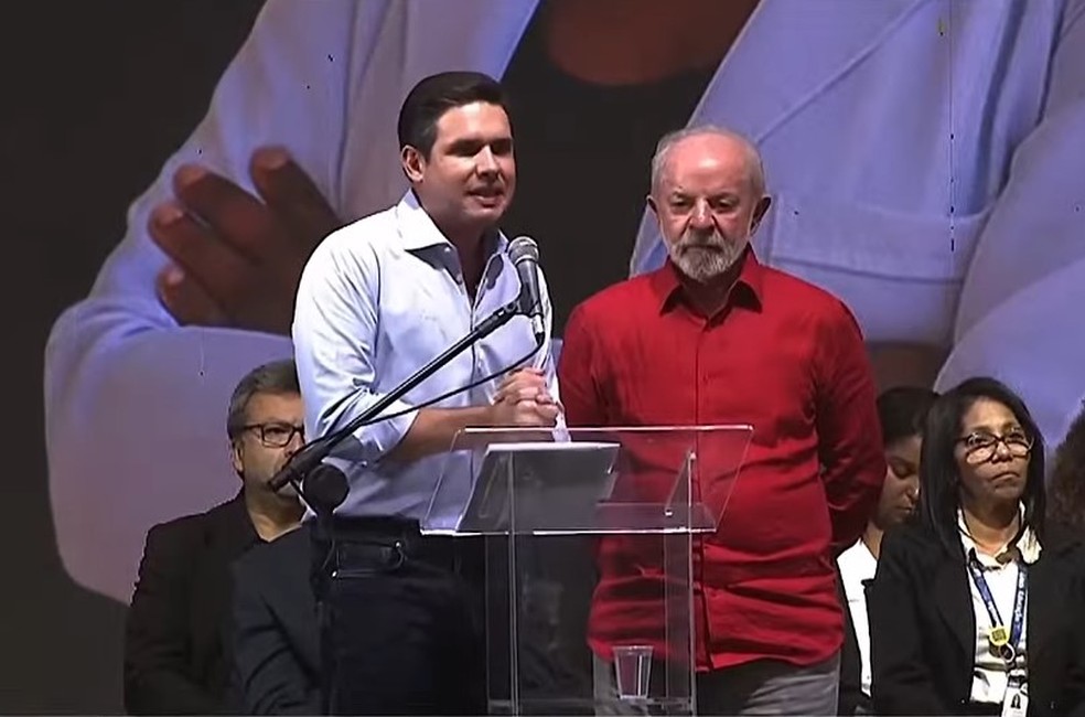 Lula discursando em evento político com Arthur Lira e outros aliados.