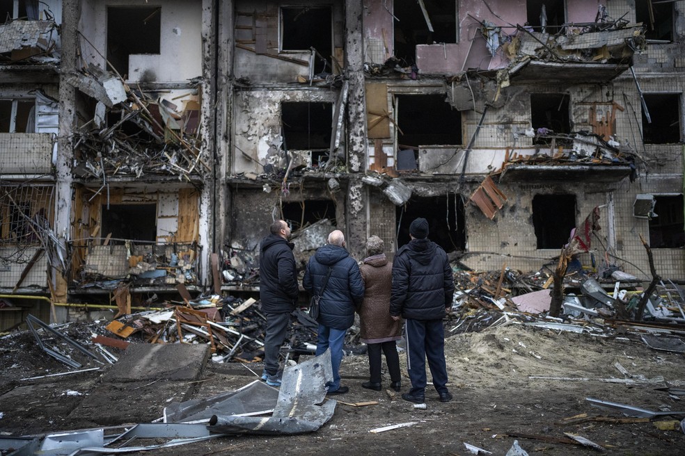 Pessoas observam os danos após um ataque com foguete na cidade de Kiev, Ucrânia — Foto: Emilio Morenatti/AP
