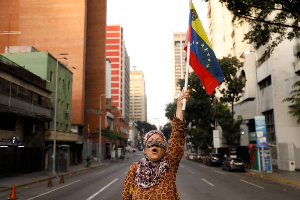 Apoiadora do presidente venezuelano Nicolás Maduro segura uma bandeira da Venezuela em uma rua perto do Palácio de Miraflores — Foto: Leonardo Fernandez Viloria/REUTERS