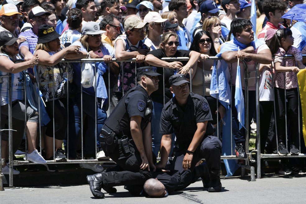 A polícia detém um homem enquanto apoiadores do novo presidente Javier Milei esperam para vê-lo indo para a casa do governo em Buenos Aires, Argentina, no domingo, 10 de dezembro de 2023 — Foto: AP Photo/Rodrigo Abd