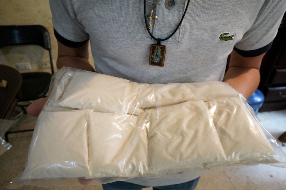 Um integrante do Cartel de Sinaloa exibe pacotes de metanfetamina em uma casa segura em Culiacán, no México — Foto: REUTERS/Alexandre Meneghini