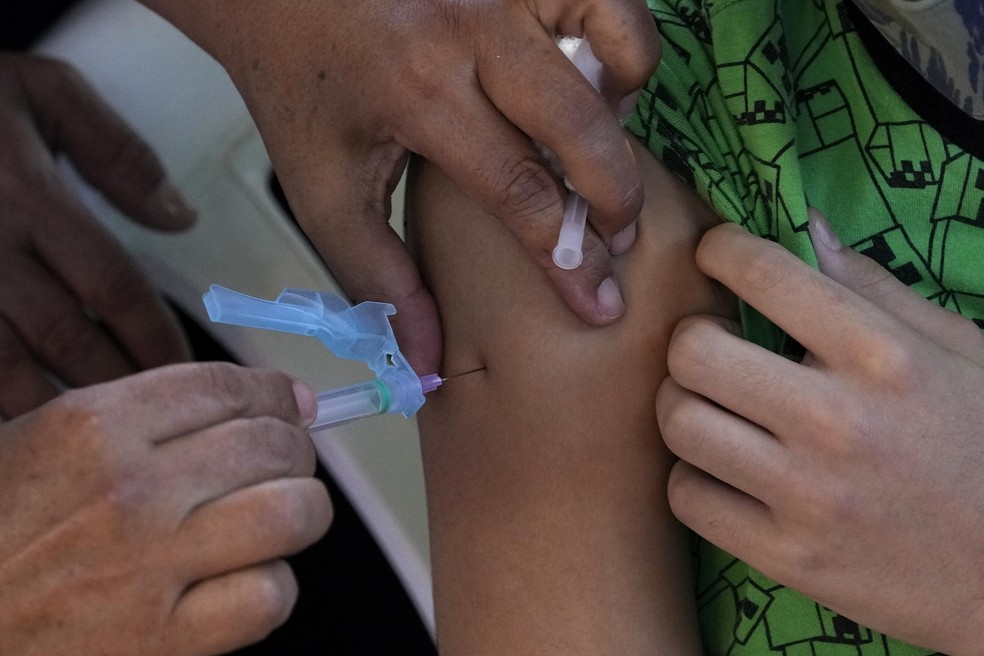 A health worker applies a shot of the Pfizer COVID-19 vaccine at a community health center in Brasilia, Brazil, Sunday, Jan. 16, 2022. Brasilia started the COVID-19 vaccination of children between age — Foto: Eraldo Peres/AP