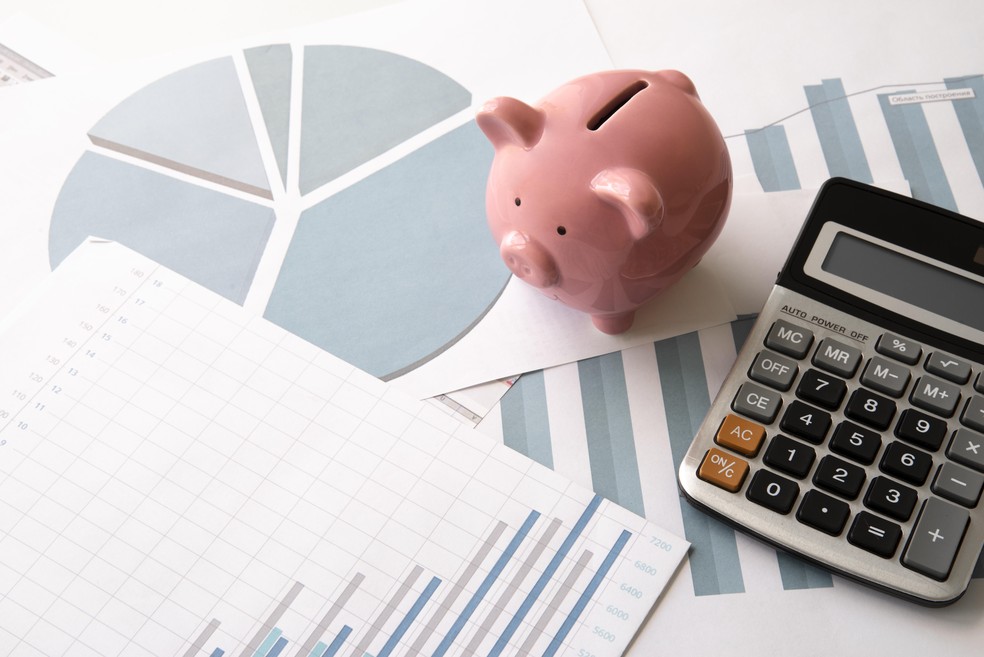 Objetos relacionados à educação e economia em um close-up, simbolizando o orçamento e as diretrizes.