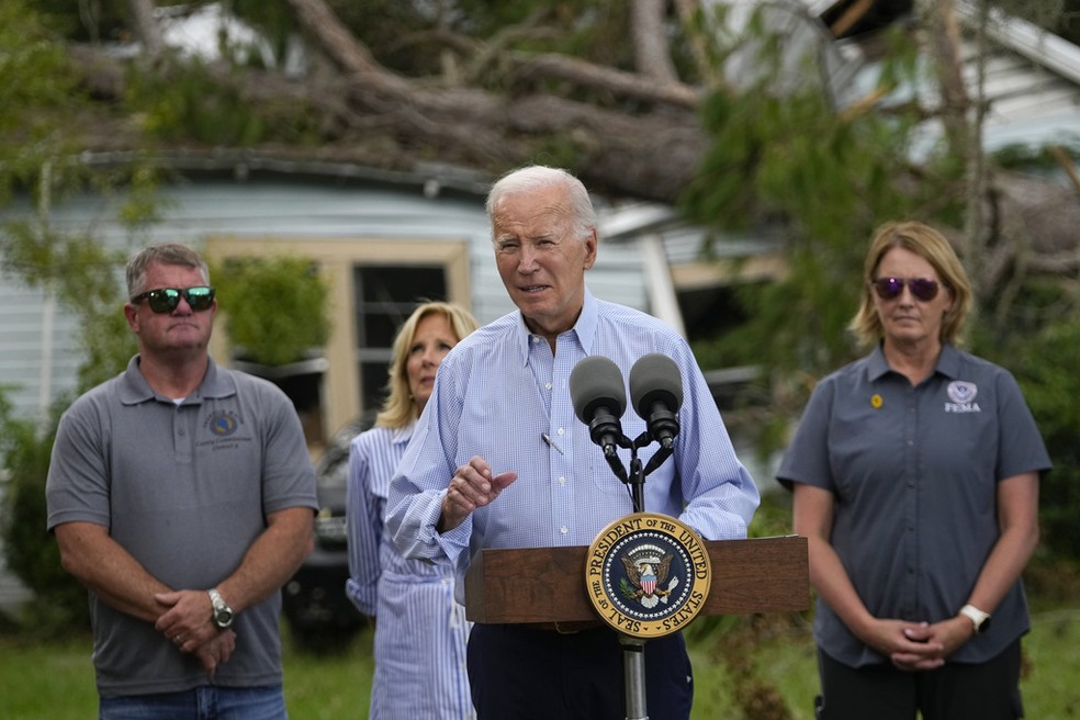 O presidente Joe Biden fala em frente a uma casa parcialmente destruída pela queda de uma árvore em Live Oak, Flórida, após a devastação causada pelo furacão Idalia. Atrás de Biden, sua esposa, Jill Biden — Foto: AP Foto/Julio Cortez