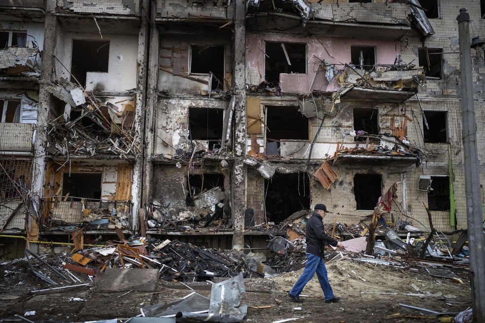 Um homem passa por um prédio danificado após um ataque com foguete na cidade de Kiev, Ucrânia — Foto: Emilio Morenatti/AP