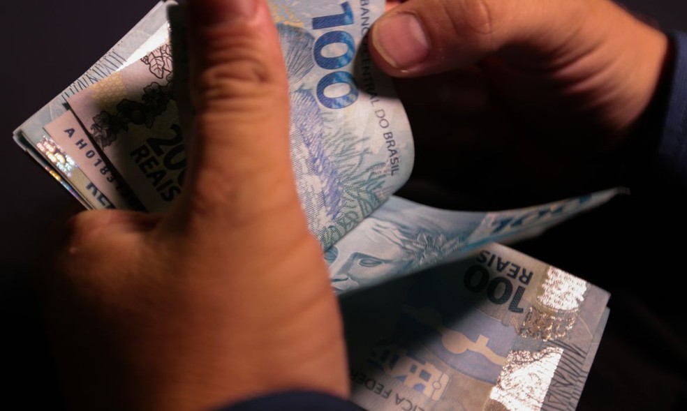 Notas de R$ 100 nas mãos de um trabalhador  — Foto: Marcelo Casal Jr./Agência Brasil
