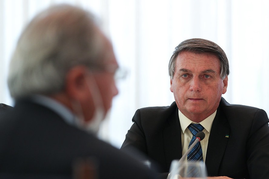 O presidente Jair Bolsonaro observa o ministro da Economia, Paulo Guedes