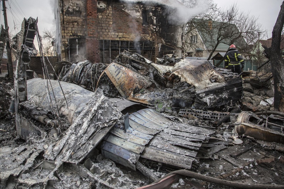 Um bombeiro ucraniano caminha entre os fragmentos de uma aeronave derrubada vista em Kiev, Ucrânia — Foto: Oleksandr Ratushniak/AP