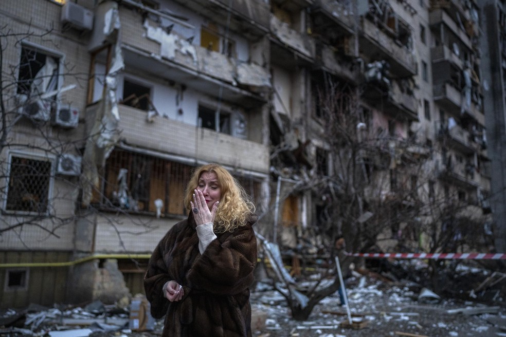 Mulher reage ao lado de sua casa após um ataque com foguete na cidade de Kiev, Ucrânia — Foto: Emilio Morenatti/AP