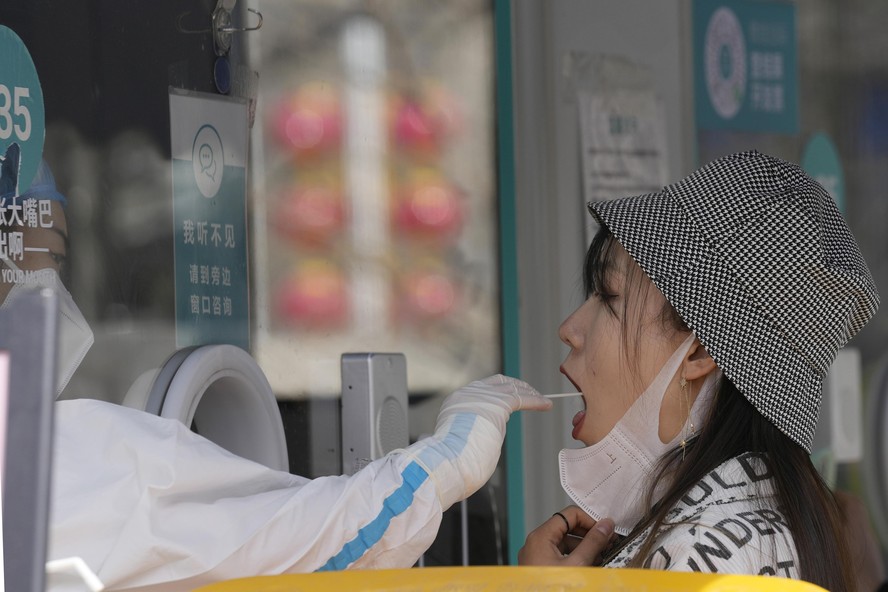 A worker takes a swab sample for a COVID-19 test at a mobile testing site on Tuesday, March 15, 2022, in Beijing. China's new COVID-19 cases Tuesday more than doubled from the previous day as the coun