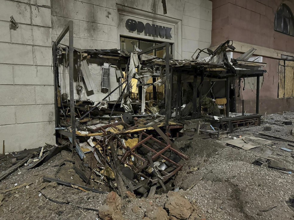 Nesta foto, em Kharkiv, uma cratera aberta por um míssil em frente a uma loja no centro da cidade após o ataque da Rússia em Kharkiv, na Ucrânia, domingo, 31 de dezembro de 2023 — Foto: Administração Regional de Kharkiv via AP