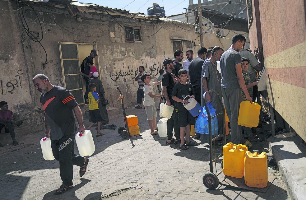 Palestinos fazem fila para encher galões com água potável em Khan Yunis, mais ao sul da Faixa de Gaza — Foto: Fatima Shbair/AP