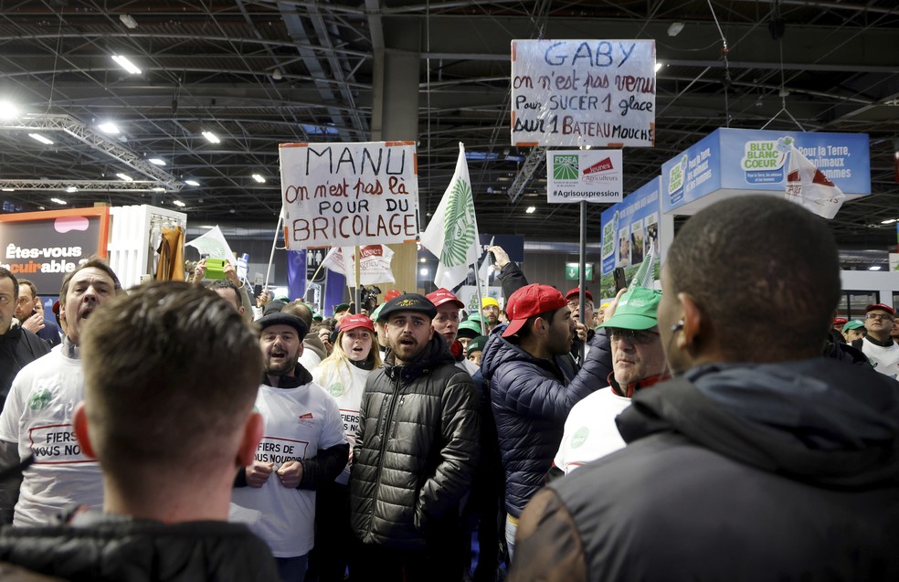 Farmers wearing union shirts protest at the International Agriculture Fair as French President Emmanuel Macron tours the exhibition on the opening day in Paris, Saturday, Feb. 24, 2024. Farmers across Europe have been protesting for weeks over what they say are excessively restrictive environmental rules — Foto: Ludovic Marin/Pool via AP