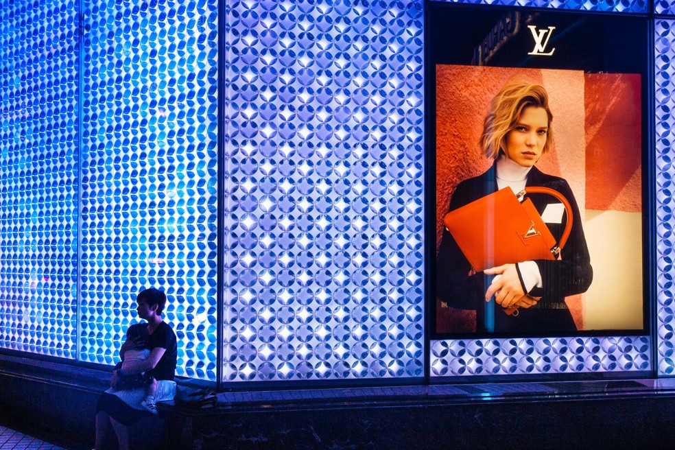 Mulher e criança em frente a anúncio da Louis Vuitton em Hong Kong. Há um consenso cada vez maior entre os economistas de que a desigualdade, tanto dentro dos países quanto entre eles, reduz o crescimento econômico — Foto: Anthony Kwan/Bloomberg