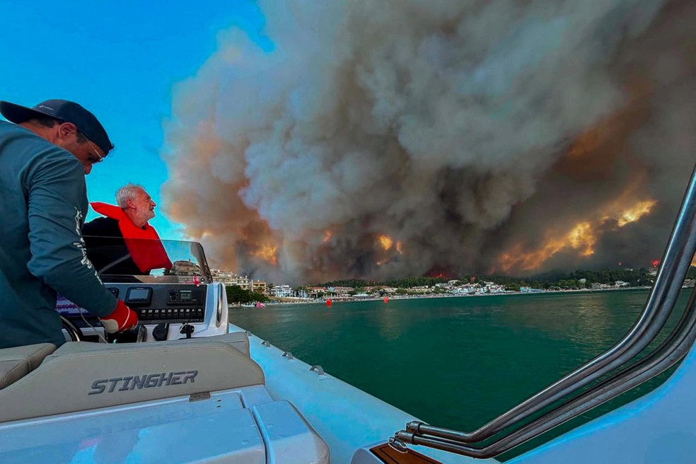 Um incêndio florestal se aproxima do balneário de Siviri, visto de uma embarcação usada na retirada de pessoas da região, na península de Halkidiki, Grécia, em 13 de agosto de 2026 — Foto: REUTERS/George Koutitas