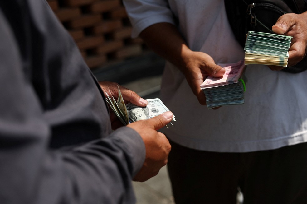 Um cambista conta dólares americanos no Grande Bazar de Teerã, Irã, em 17 de agosto de 2026 — Foto: Majid Asgaripour/WANA (West Asia News Agency) via REUTERS