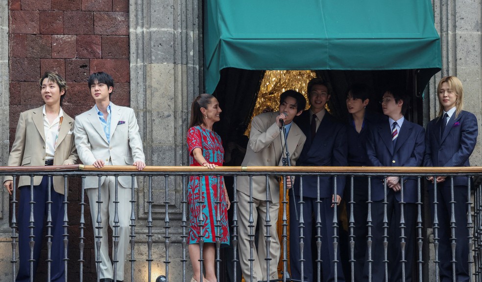 V, da boy band sul-coreana de K-pop BTS , fala enquanto a presidente do México, Claudia Sheinbaum, reage ao lado de outros membros da banda, em uma varanda do Palácio Nacional, antes de uma série de shows da turnê mundial 'Arirang' do BTS , na Cidade do México, México, em 6 de maio de 2026. — Foto: REUTERS/Luis Cortes