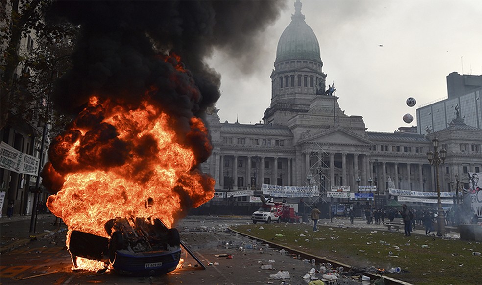 Carro incendiado por manifestantes na frente do Congresso argentino — Foto: AP