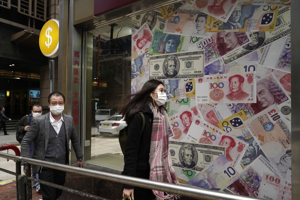 Pessoas se protegem do coronavírus em frente a casa de câmbio em Hong Kong  — Foto: AP Photo/Kin Cheun
