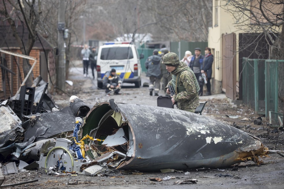 Um soldado do Exército ucraniano inspeciona fragmentos de uma aeronave derrubada em Kiev, Ucrânia — Foto: Vadim Zamirovsky/AP